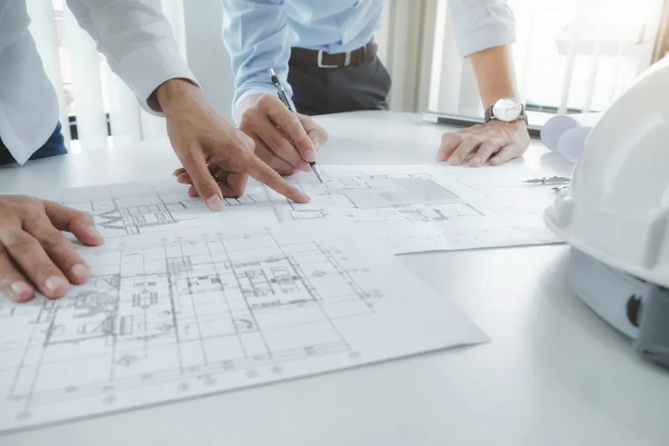 Teknik çizimler üzerinde proje planını inceleyen mühendisler